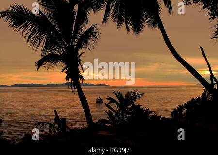The sun setting over a tropical island in the Indian ocean image with copy space in landscape format Stock Photo