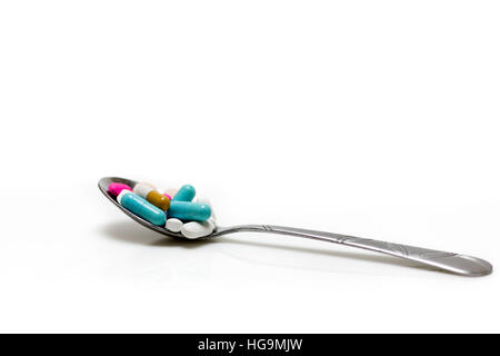 Silver spoon with assorted pills isolated on a white background. Stock Photo