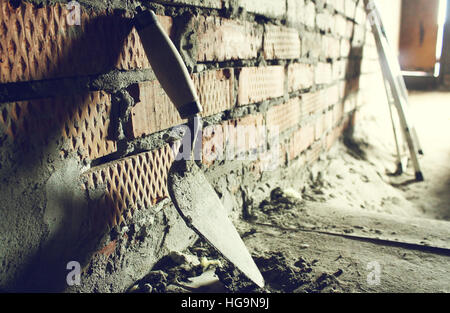 Trowel on a brick wall background Stock Photo