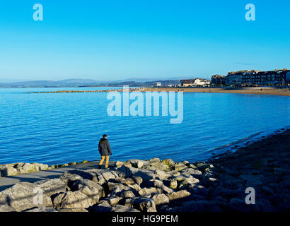 Man walking down to the beach at high tide, Morecambe, Lancashire, England UK Stock Photo