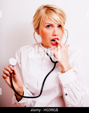 funny doctor with stethoscope, smiling blond woman medical equipment showing on white background Stock Photo