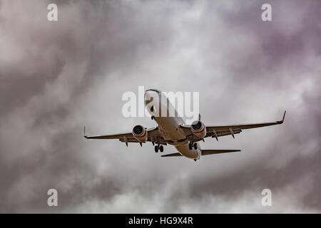 Passenger jet airplane low in the sky preparing to land with stormy clouds in the background Stock Photo