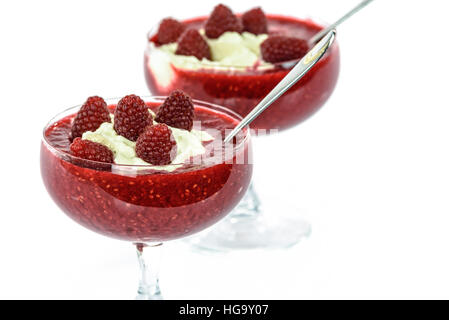Raspberries and whipped cream in glass cups isolated on white background Stock Photo