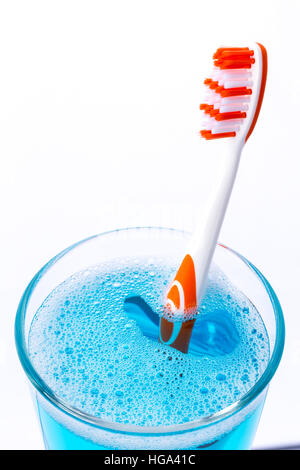Toothbrush in glass with mouth rinse isolated on white, closeup. Stock Photo