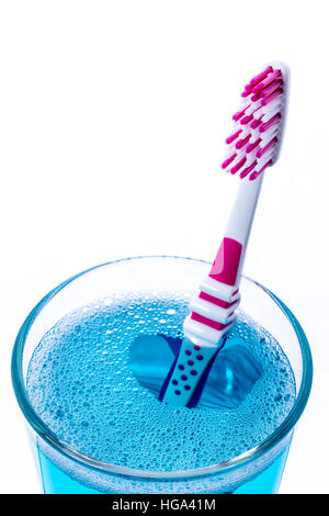 Toothbrush in glass with mouth rinse isolated on white, closeup. Stock Photo