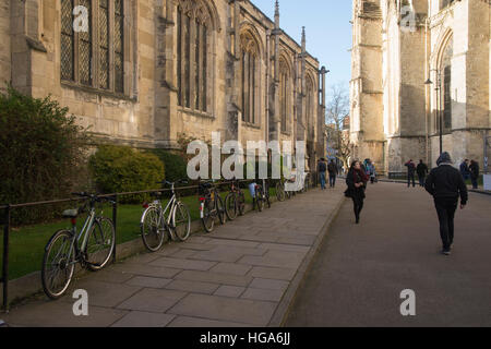 People pass row of bikes attached to railings outside the Church of St. Michael Ie Belfrey opposite York Minster, York, England. Stock Photo