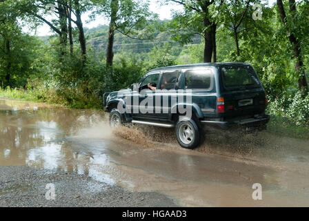 Jeep car driving through mud water flooded road in countryside area of London Stock Photo