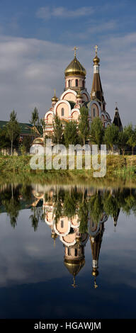 Vertical panorama of the Church of the Exaltation of the Holy Cross in Almaty Kazakhstan reflected in still lake Stock Photo