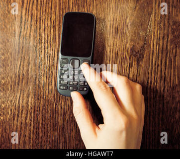 Womans hand using classic cell phone blank screen top view Stock Photo