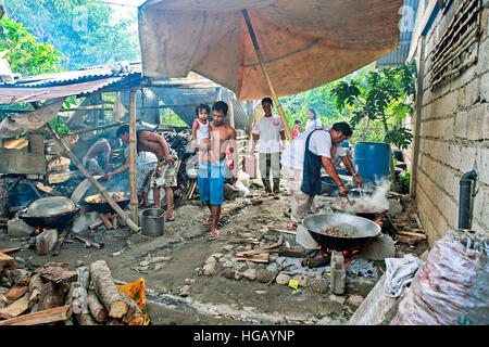 Filipino extended families cook food in their outdoor dirty kitchen. Stock Photo
