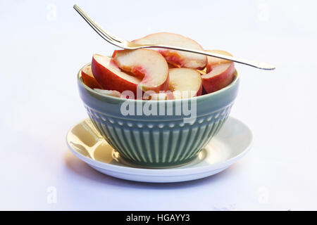 Fresh peaches in a green bowl on white background Stock Photo