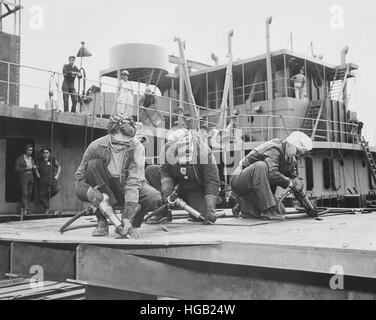 Three women chippers working in a shipbuilding shipyard. Stock Photo