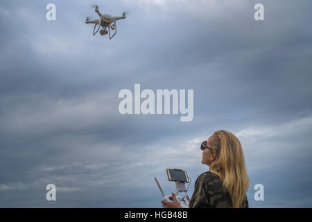 Happy woman standing with remote controller of drone over cloudy sky background Stock Photo