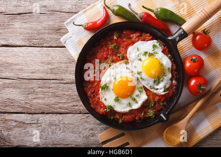 Mexican fried eggs huevos rancheros close-up in a frying pan on the table. horizontal view from above Stock Photo