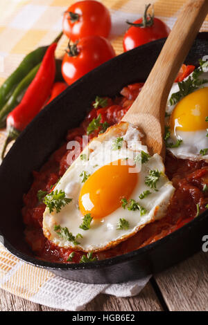 Mexican breakfast huevos rancheros: fried egg with salsa closeup in the pan. vertical Stock Photo