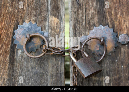 Old wooden gates locked on iron padlock with chain in bulgarian village Stock Photo