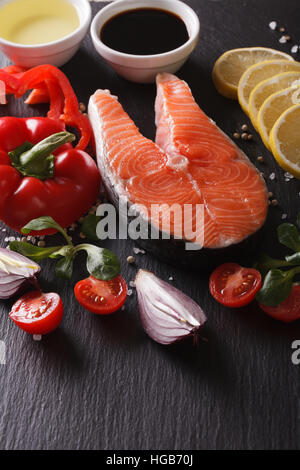 Raw salmon steak and ingredients on a slate board closeup. vertical Stock Photo