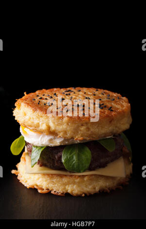 New ramen burger with beef and eggs close-up on a black background. Vertical Stock Photo