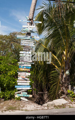 Holiday Sign to Everywhere. A tree trunk turned into a sign to vacationers hometowns with mileage and directions to each. Hopetown, Abaco, Bahamas Stock Photo