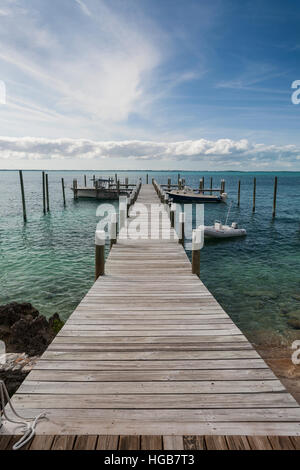 Lets Go Boating vertical. The long dock at Firefly seems to draw one toward some fun boating on the calm Sea of Abaco Stock Photo