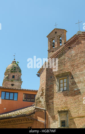 Two historic brick churches with towers in contrast to more modern orange house in Siena, Italy, Europe Stock Photo