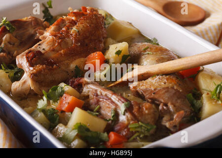 Pieces of chicken stewed with potatoes and carrots in a dish close-up. Horizontal Stock Photo