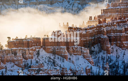 A ridge of hoodoos covered in snow and silhouetted against the fog in Bryce Canyon National Park, Utah Stock Photo