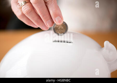 a woman's hand doing euros in a piggy bank in order to save for unforeseen circumstances Stock Photo