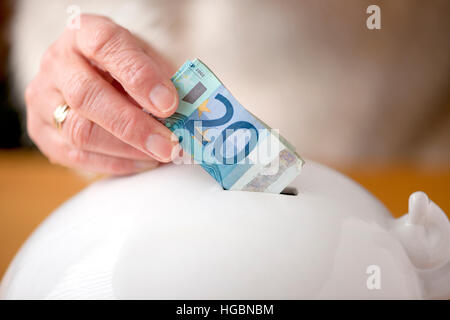 a woman's hand doing euros in a piggy bank in order to save for unforeseen circumstances Stock Photo