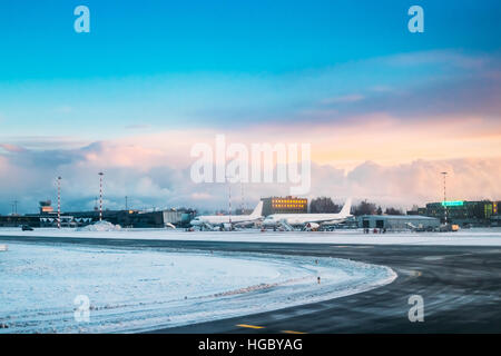 Riga, Latvia - December 1, 2016: Aircraft stand at the Riga International Airport terminal in early morning with beautiful sunrise dramatic sky. Stock Photo