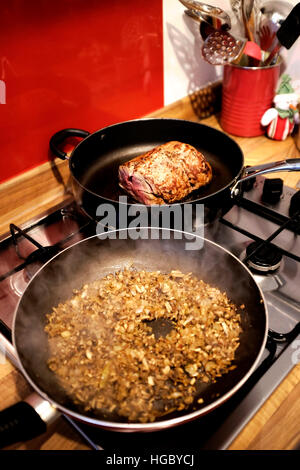 Fillet of beef being browned off and sealed in frying pan plus mushrooms and onions for a duxelles  to make Beef Wellington dish Stock Photo