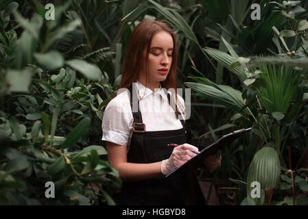 Female florist with clipboard at the greenhouse Stock Photo