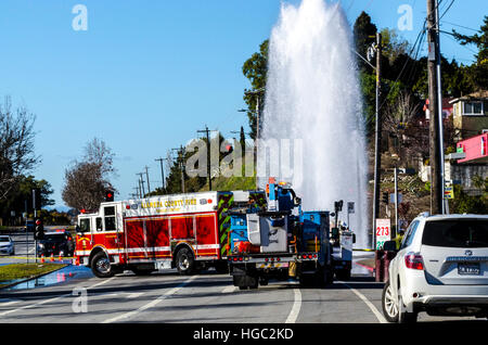 A fire hydrant broken off by a truck creates a geyser and small flood in San Leandro California Stock Photo