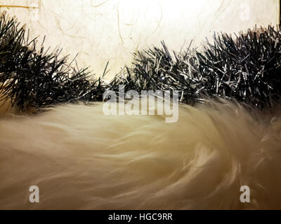 Close up of off white fur carpet under warm light with silver ribbon garland on it in front of mulberry paper lantern with warm lamp inside. Stock Photo