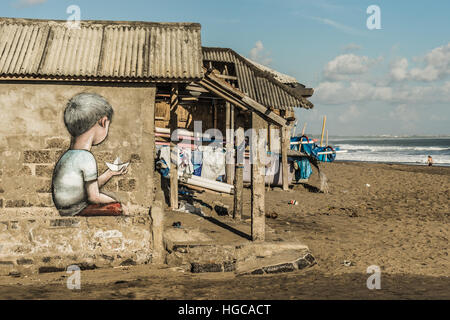 'Floating Away' Graffiti of a boy holding a paper boat on a beach shack, Canggu Bali, Indonesia. Stock Photo