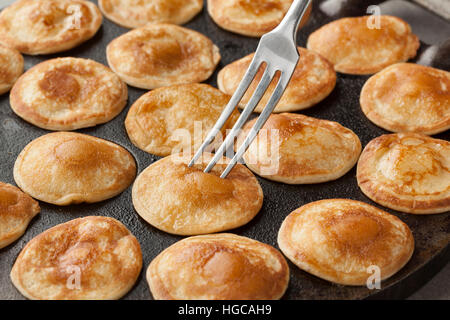 Baking Dutch mini pancakes called poffertjes in a special skillet pan Stock Photo