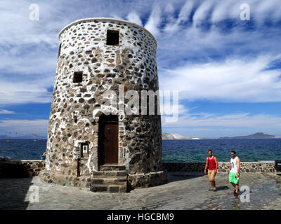 A disused Greek windmill building, with the sea and islands in the distance. Stock Photo