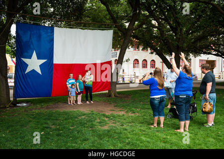 Fort Worth, Texas, USA - June 10, 2014: Family taking a photo in front of the Texas Flag in the Fort Worth Stockyards, Forth Worth, Texas Stock Photo