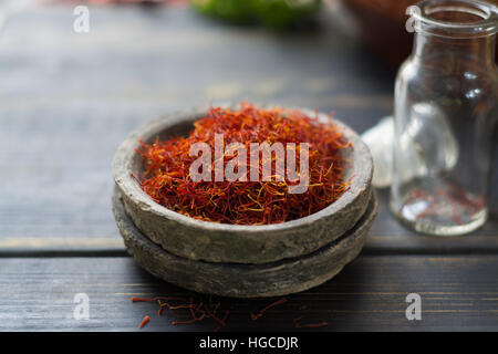 Raw Organic Red Saffron Spice in a clay bowl on wooden table Stock Photo