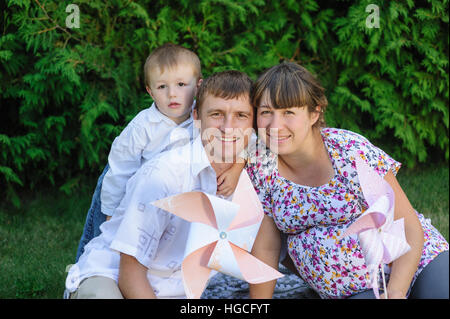 young family sitting on lawn in summer Park Stock Photo