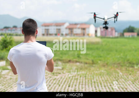 Man Operating Drone Flying or Hovering by Remote Control in Nature Stock Photo