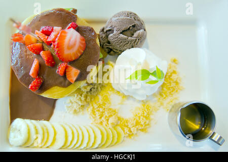 Low fat homemade chocolate ice-cream with strawberry, whip cream served with sliced banana, chocolate filled crepe and natural honey, a perfect sweet Stock Photo