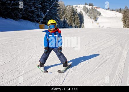 Cute little boy, skiing happily in Austrian ski resort in the mountains, wintertime Stock Photo