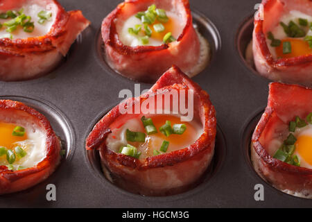 freshly baked hot eggs wrapped in bacon close up in baking dish. Horizontal Stock Photo