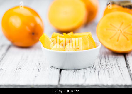 Fresh made Kakis on an old and rustic wooden table (selective focus, close-up shot) Stock Photo