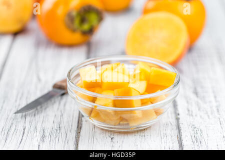 Kaki fruits on rustic wooden background (close-up shot) Stock Photo