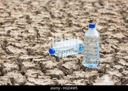 Bottle with water on the dried ground. Stock Photo