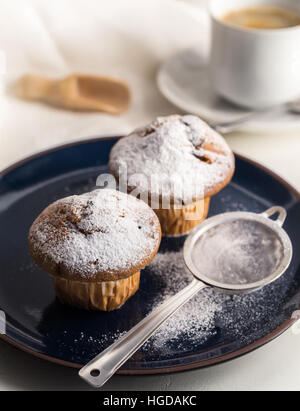 Breakfast with muffins with powdered sugar on dark blue plate. Stock Photo