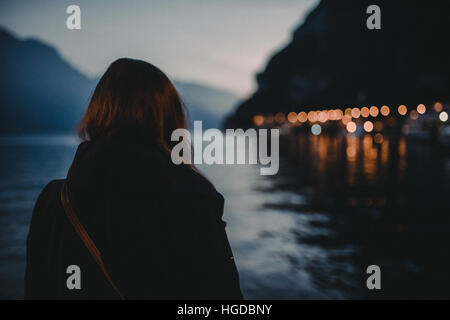 A woman in a black coat looking over the Lake Garda in Italy with a blurry background Stock Photo
