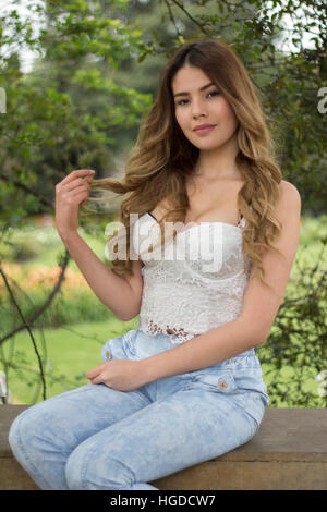 Beautiful girl sitting on a chair in a park Stock Photo